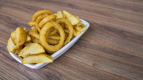 A delicious serving of crispy onion rings and potato wedges on a wooden table.