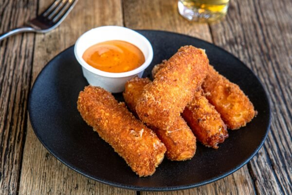 Delicious homemade mozzarella sticks with spicy dipping sauce, perfect for snack time.