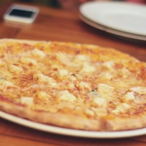 Close-up of a cheese pizza on a wooden table, ready to be served and enjoyed.