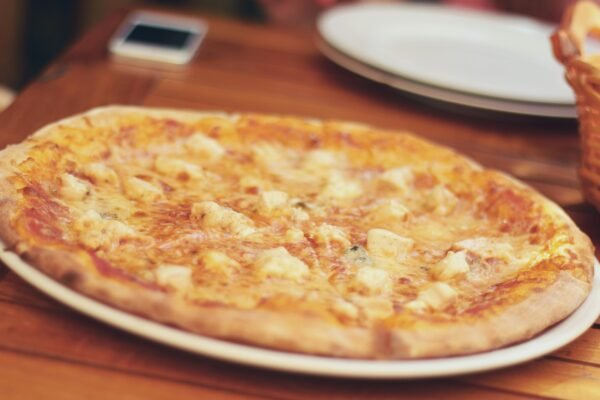 Close-up of a cheese pizza on a wooden table, ready to be served and enjoyed.